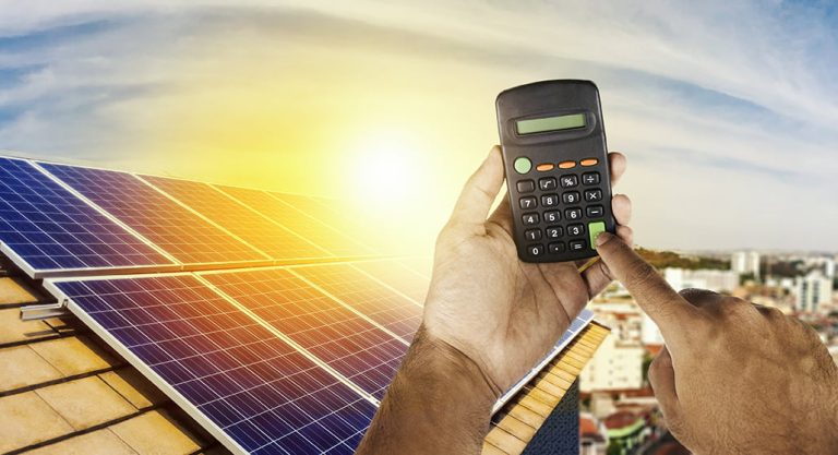 Holding a calculator on a solar panel photovoltaic installation